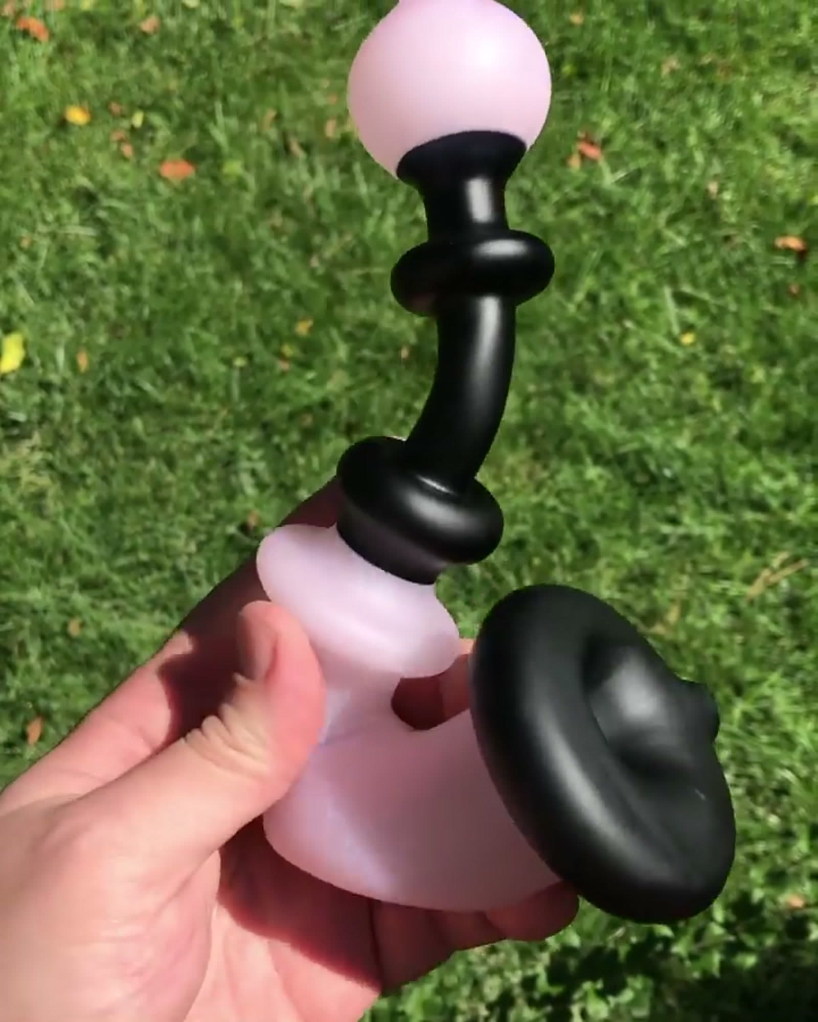 A matte pink and black functional piece held in one hand.